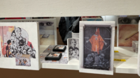 Image of pieces of art exhibited in the Reckless Law, Shameless Order: An Intimate Experience of Incarceration exhibit located in the Hood Classroom of Krannert Art Museum. In the art there can be seen representations of soldiers, skulls, a red cloaked figure, the holy trinity, and other forms of brutality.