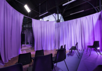 image of sheets surrounding black chairs with a purple reflection.