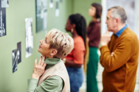 Image of elderly admiring photos and art on a green wall