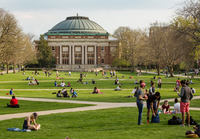 Foellinger Auditorium on a spring day. Students are relaxing on the grass enjoying the weather.