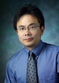 Photo of Dr. Fengyi Wan. He has wire-framed glasses and dark hair and is wearing a blue shirt with contrasting blue tie.