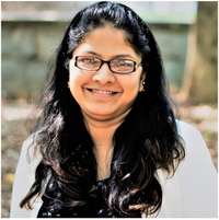 Photo of Prof. Neha Garg. She has dark-framed glasses and is smiling.